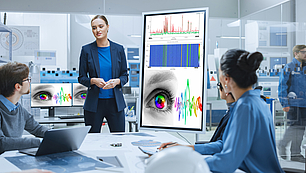 Expert-led training and support session for spectrum monitoring Business professionals in a high-tech meeting room receiving expert training with spectrum monitoring visualizations on screen