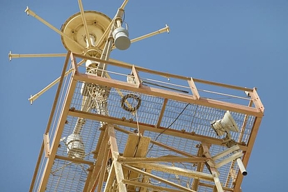 Communication or Radar Tower A tall communication or radar tower with metal framework and various antennas and equipment mounted on it, set against a clear blue sky.